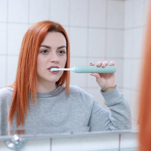 Kobieta myje zęby szczoteczką soniczną